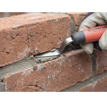 Een voegspijker van Maurerlob wordt gebruikt om mortel in de voeg tussen twee rode bakstenen te drukken.
