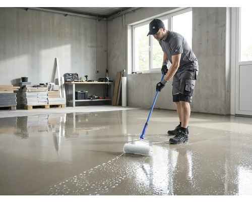 Een man gebruikt een prikroller met telescoopsteel om een vers gegoten vloercoating te ontluchten in een lichte ruimte.