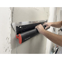 Een persoon gebruikt een Maurerlob-oppervlaktespatel om nat pleisterwerk op een muur glad te strijken.