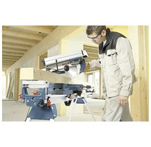 Vakman zaagt een houten balk met een Bosch afkort- en verstekzaag op een werktafel in een lichte bouwomgeving.