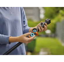 Een persoon plaatst een blauwe afdichtingsring of filter in een zwarte gietstaaf voor tuinbewatering.