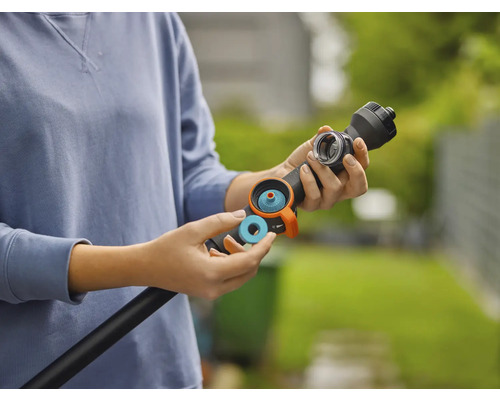 Een persoon plaatst een blauwe afdichtingsring of filter in een zwarte gietstaaf voor tuinbewatering.
