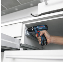 Bosch Professional accuboorschroefmachine bij de montage van metalen ladegeleiders in een witte kast.