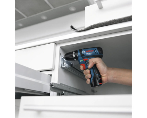 Bosch Professional accuboorschroefmachine bij de montage van metalen ladegeleiders in een witte kast.