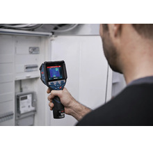 Persoon controleert een elektrische installatie in een verdeelkast met een Bosch warmtebeeldcamera.
