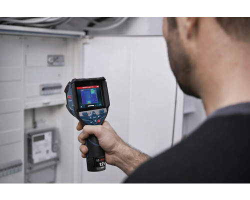 Persoon controleert een elektrische installatie in een verdeelkast met een Bosch warmtebeeldcamera.