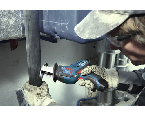 Vakman snijdt een donkere pijp door met een Bosch Professional accu-reciprozaag in een werkruimte met zilverkleurige metalen buizen.