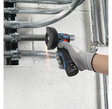 Bosch Professional 12 Volt accu haakse slijper snijdt een metalen buis aan een wand met zichtbare vonken.