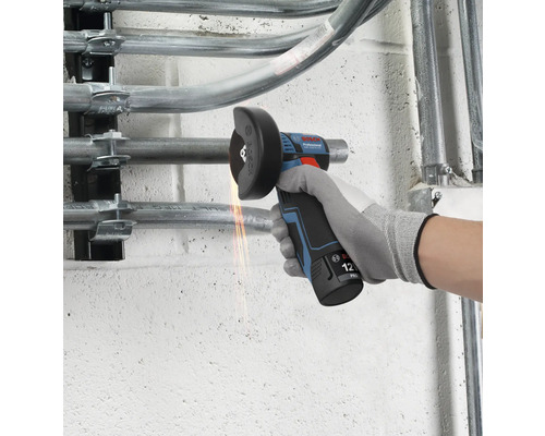 Bosch Professional 12 Volt accu haakse slijper snijdt een metalen buis aan een wand met zichtbare vonken.