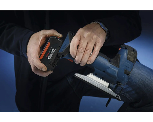 Een persoon plaatst een accu uit het Bosch Professional 18 volt systeem in een decoupeerzaag.