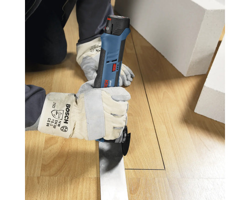 Persoon met werkhandschoenen snijdt met een Bosch Professional accu-multitool een rechte lijn in een houten vloer.