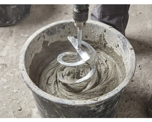 Een spiraalvormige mengstaaf mengt grijze mortel in een zwarte bouwemmer.