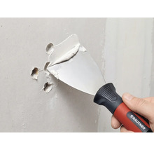 RAUTNER plamuurmes vult gaten in een muur met vulmiddel.