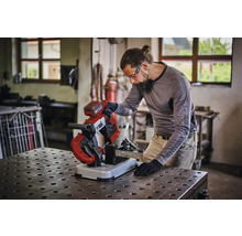 Een persoon gebruikt een accu metaalbandzaag voor het zagen van een metaalprofiel op een werkbank in een werkplaats.