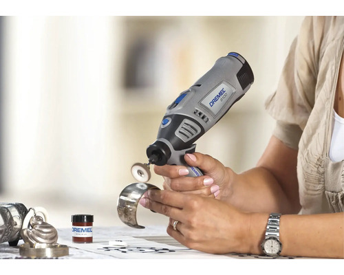 Een persoon gebruikt een Dremel 8100 accu-multitool met polijstaccessoire om een metalen armband te polijsten.