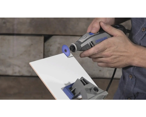 Dremel multifunctioneel gereedschap bij het snijden van een witte tegel met een doorslijpschijf.