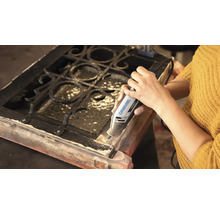 Persoon gebruikt een Dremel 4250 multifunctioneel gereedschap voor het bewerken van een houten frame met metalen rooster.