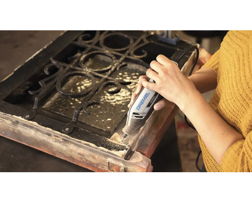 Persoon gebruikt een Dremel 4250 multifunctioneel gereedschap voor het bewerken van een houten frame met metalen rooster.