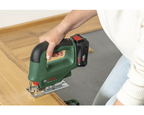 Een persoon snijdt een stuk laminaat met een Bosch accu-decoupeerzaag EasySaw 18V-70.