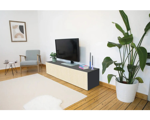 Moderne woonkamer met tv-meubel voorzien van verticale houten latten, televisie, fauteuil en kamerplant op een houten vloer.