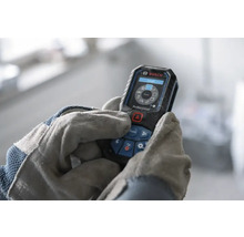 Bosch Professional laserafstandsmeter bediend door handen in werkhandschoenen, digitaal display met meetfuncties.