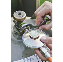 Een persoon sluit een gasdrukregelaar aan op het ventiel van een gasfles met behulp van een CFH gassleutel.