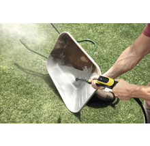 Een vuile kruiwagen op een gazon schoonmaken met een hogedrukreiniger.