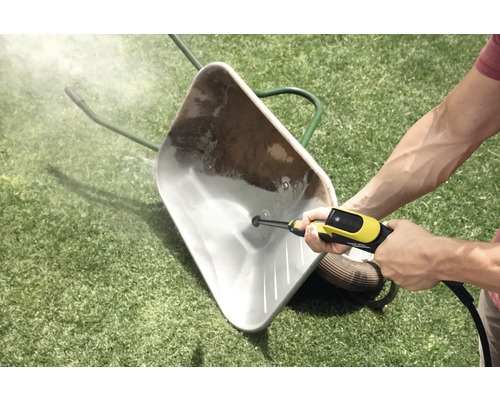 Een vuile kruiwagen op een gazon schoonmaken met een hogedrukreiniger.