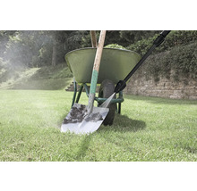 Een hogedrukreiniger reinigt een vuile schep voor een groene kruiwagen op een gazon.