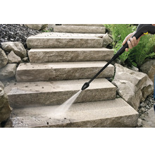 Schoonmaken van stenen trappen buiten met de waterstraal van een hogedrukreiniger.