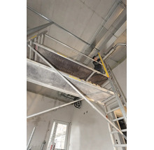 Vakman op een Layher rolsteiger tijdens installatiewerkzaamheden aan een betonnen plafond in een ruwbouw.