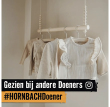 Hangende houten kledingroede met houten kralen aan touwen in een lichte babykamer, voorzien van babykleding op houten hangers. Instagram Logo.