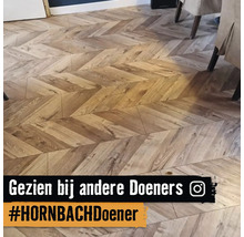 Vloerbedekking in houtlook gelegd in chevronpatroon in een lichte en georganiseerde woonruimte.