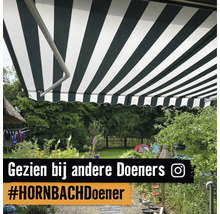 Gestreepte zonwering boven een terras in een rijk beplante tuin.