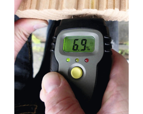 Digitale vochtmeter meet het vochtgehalte van een houten plank, het display geeft zes komma negen procent aan.
