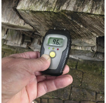 Houtvochtmeter bij het meten van de vochtigheid van brandhout met een digitale weergave van 9,6 procent.