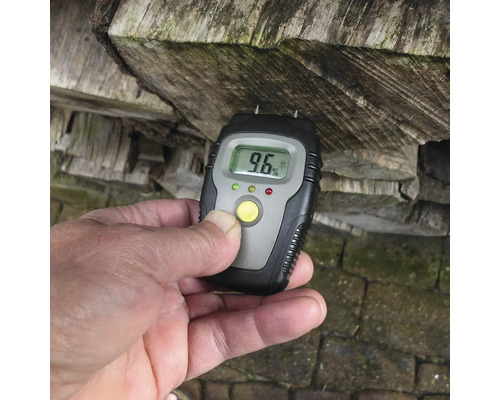 Houtvochtmeter bij het meten van de vochtigheid van brandhout met een digitale weergave van 9,6 procent.