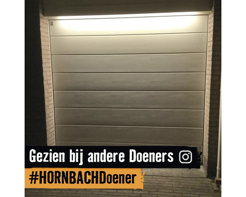 Sectionaal garagedeur met horizontale panelen in een bakstenen muur, van bovenaf verlicht door een lichtbron.