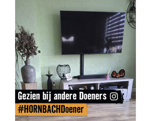 Moderne woonkamer met televisie aan een groene bakstenen muur boven een licht houten tv-meubel.