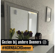 Rechthoekige wandspiegel met structuurlijst op een dressoir met tulpen voor een behangen wand. Instagram Logo.