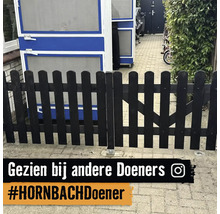 Laag houten tuinhek met afgeronde latten in een bestrate buitenruimte.