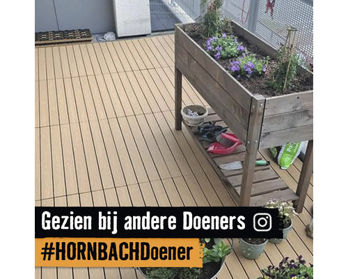 Georganiseerd balkon met terrasplanken en een houten moestuinbak op poten met bloemen en tuingereedschap op de plank.