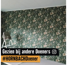 Wand met behang met bloemenpatroon naast een trapladder.