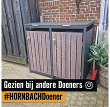 Een moderne kliko-ombouw voor twee containers met een metalen frame en deuren in houtlook, geplaatst buiten voor een bakstenen muur.