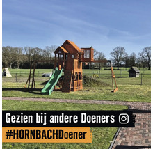 Houten speeltoestel met glijbaan, klimwand en speelhuisje in een ruime tuin.