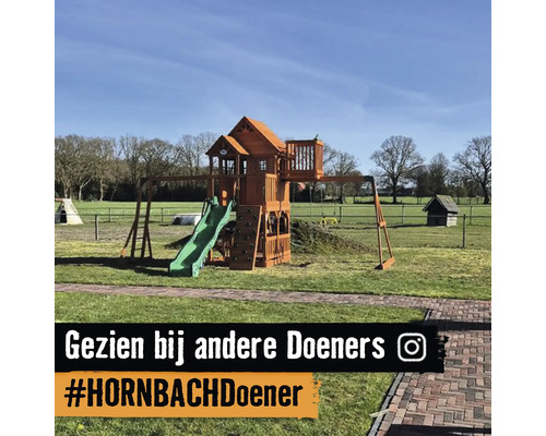 Houten speeltoestel met glijbaan, klimwand en speelhuisje in een ruime tuin.