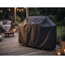 Tenneker barbecuehoes op een houten terras naast een brandende vuurschaal en tuinmeubilair bij schemering.