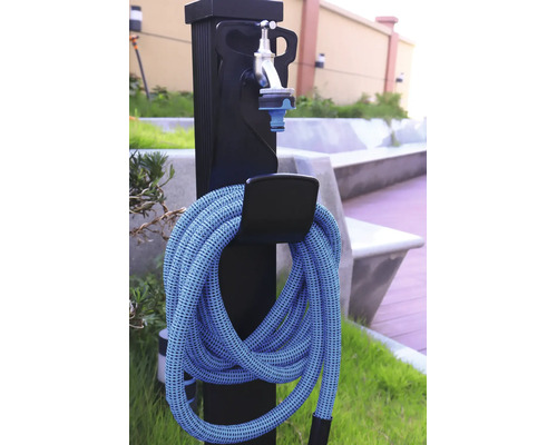 Watertappunt voor de tuin met flexibele tuinslang en waterkraan op een zwarte zuil.