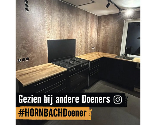 Moderne keuken met zwarte kasten, een houten werkblad, een gasfornuis en een muur met een bronzen textuurafwerking.