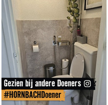 Modern toilet met wandtegels in steenlook, wit toilet, bidetdouche, afvalbak en toiletrolhouder van roestvrij staal.
